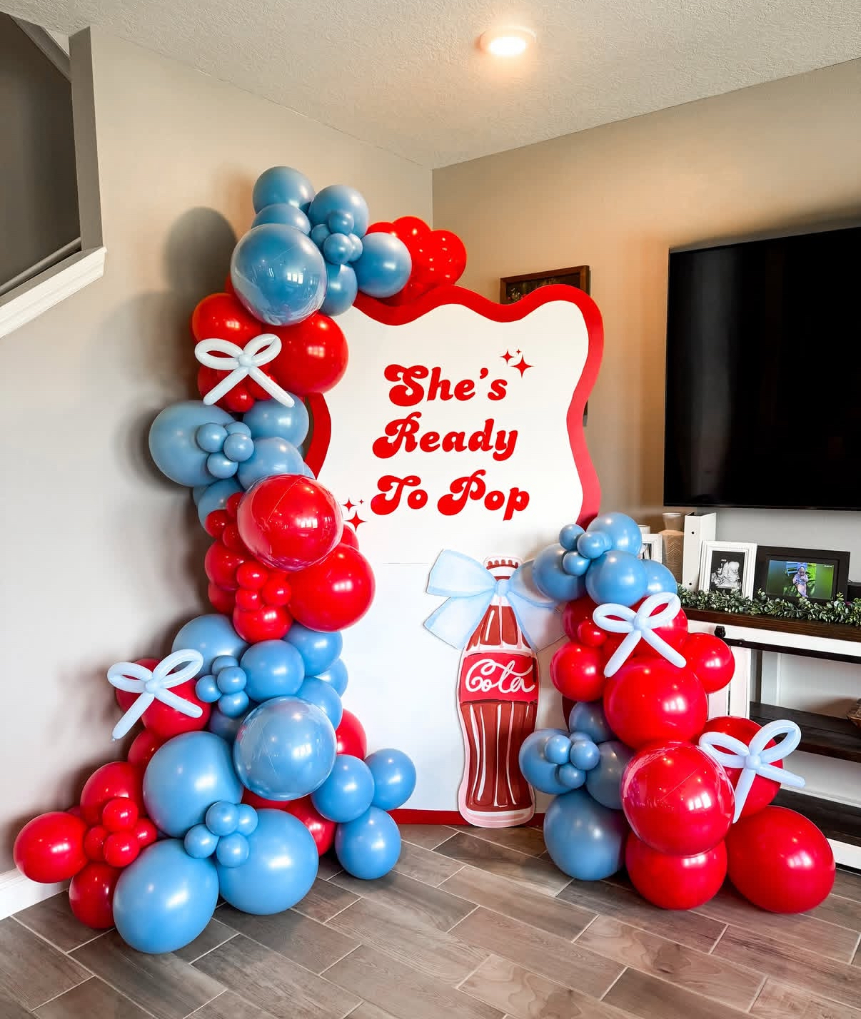 She's Ready To Pop red and blue baby shower balloon arch with cola bottle cutout